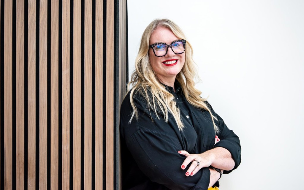 Sophie is smiling while wearing brown glasses and black shirt.