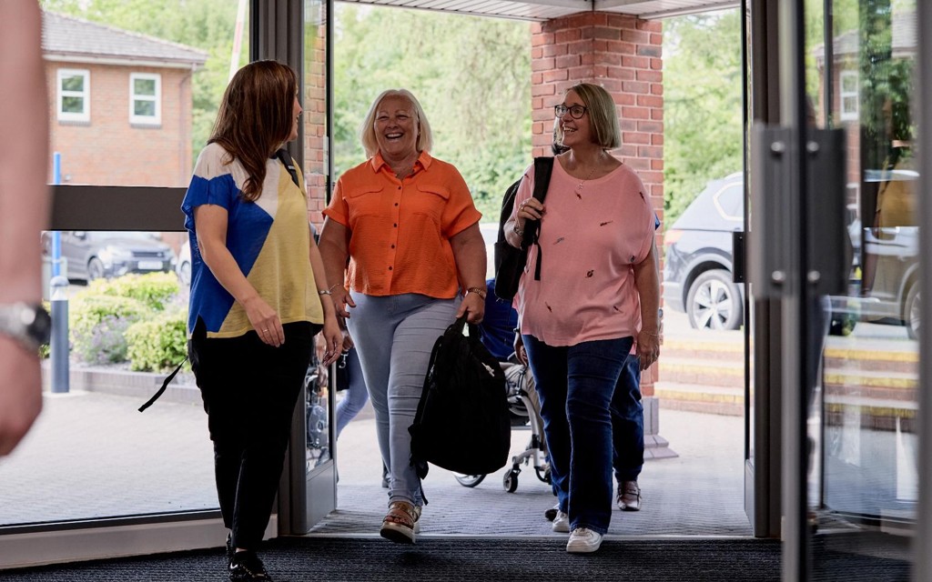 Motability Foundation colleagues are walking into their office building smiling and talking.