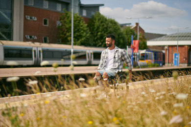A man in a wheelchair is on a train station platform on a sunny day