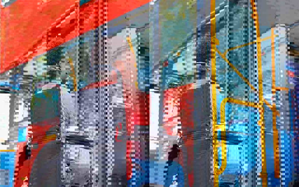 A man is sitting in a wheelchair in front of a bus.