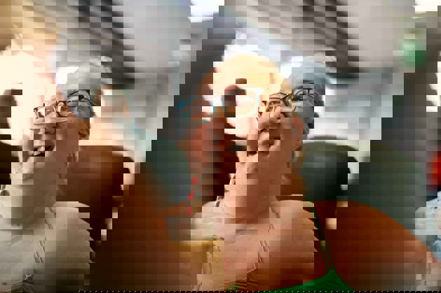 Tina is in a café. She is smiling and talking to her friend.