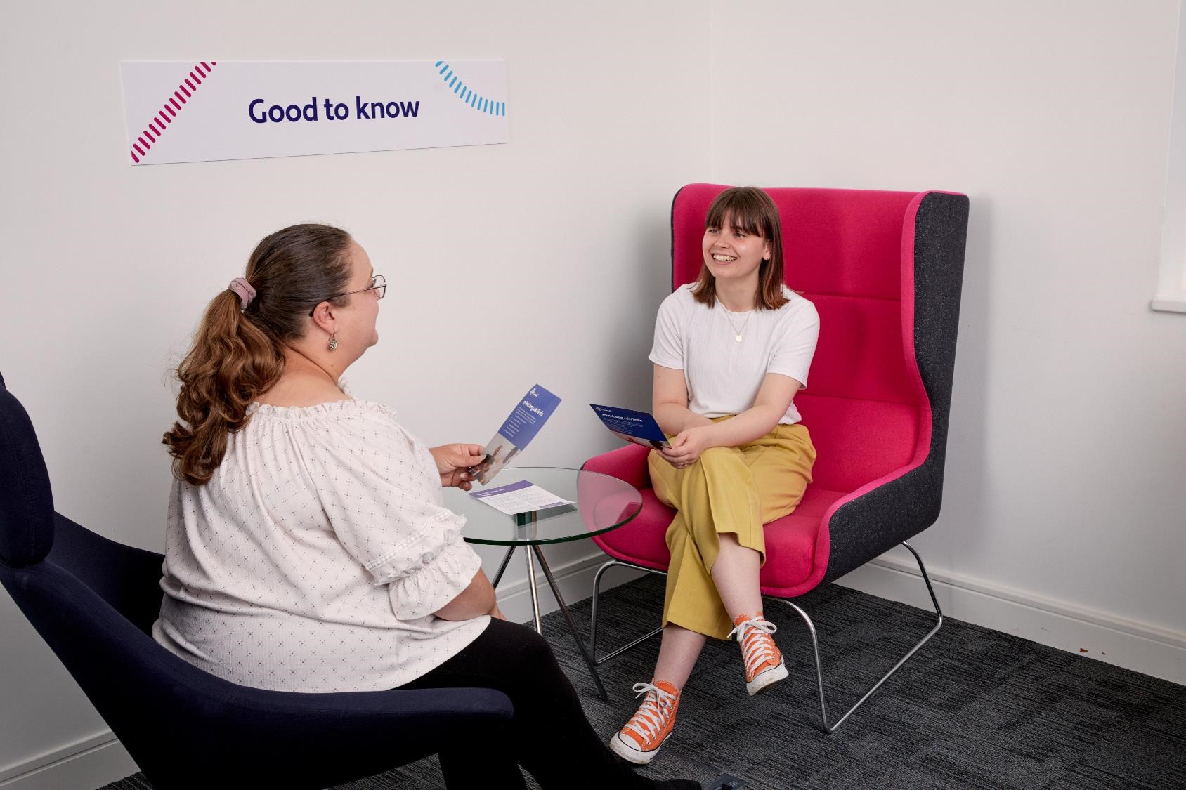 Two ladies and discussing a document and smiling.