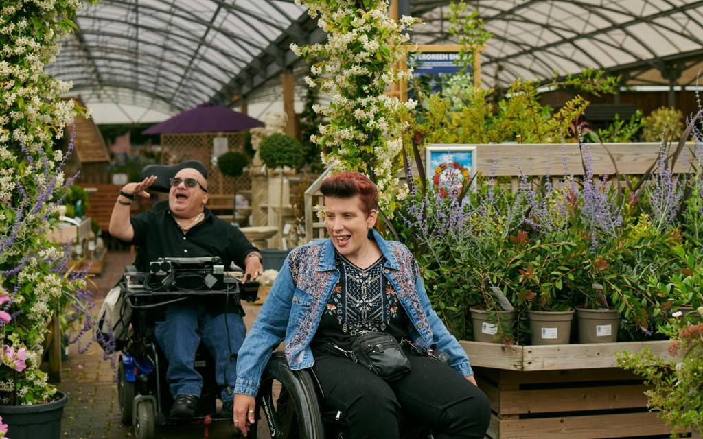 Angela and Pete are wheeling through their local garden centre looking at all the plants and chatting.