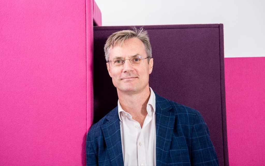 Phillip is smiling and wearing a white shirt and navy jacket.