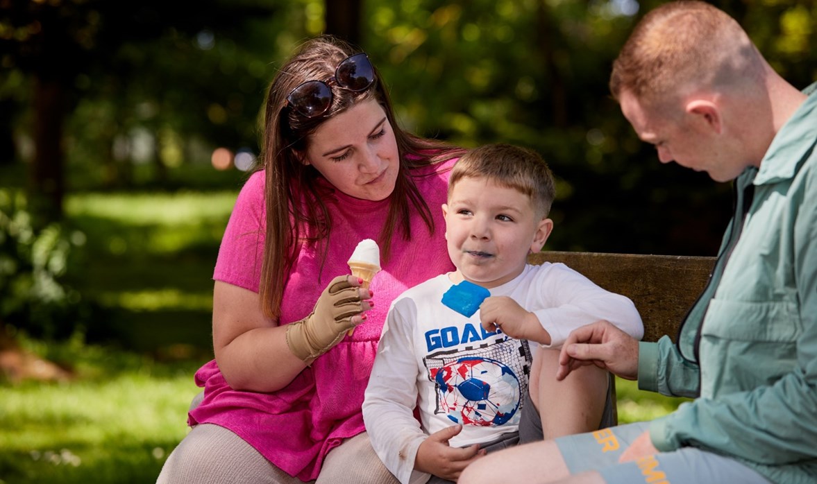 Jess is sitting with her partner and son, they are all eating an ice cream and enjoying the weather.