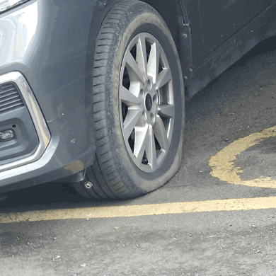 The photo shows one of the front tyres on Luis's vehicle deflated while parked in a disabled parking space, due to a nail being embedded in the tyre.