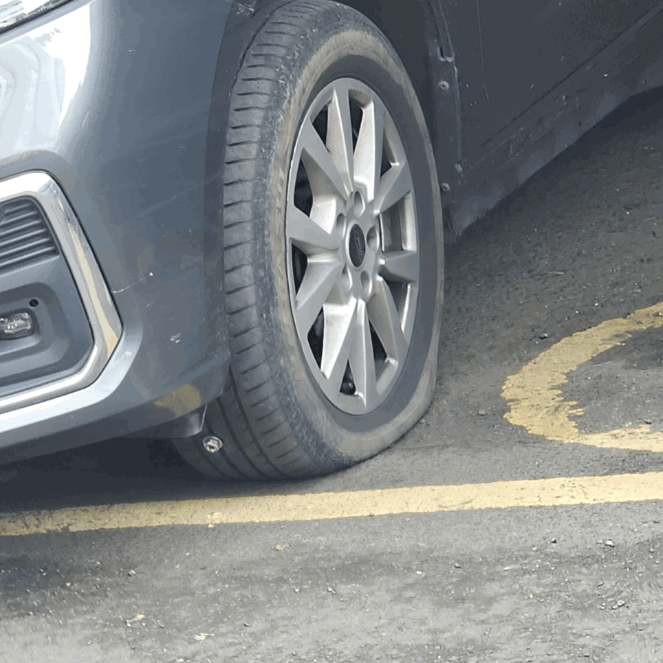 The photo shows one of the front tyres on Luis's vehicle deflated while parked in a disabled parking space, due to a nail being embedded in the tyre.