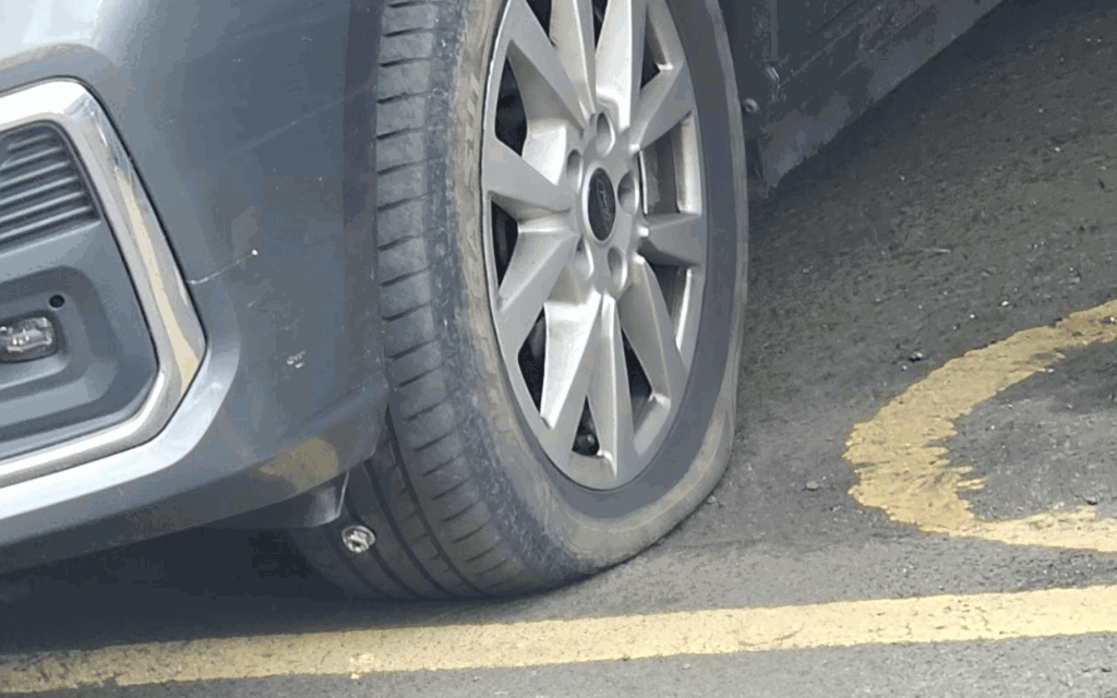 The photo shows one of the front tyres on Luis's vehicle deflated while parked in a disabled parking space, due to a nail being embedded in the tyre.