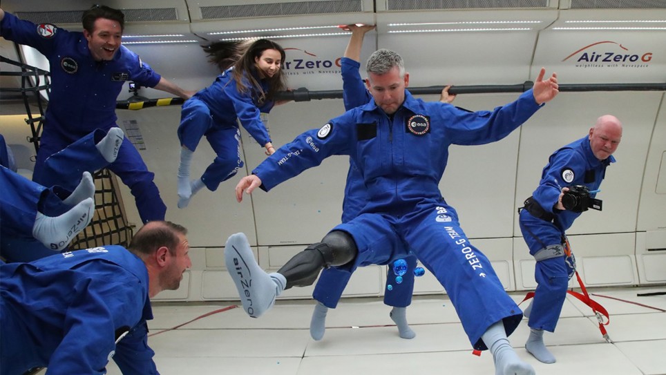 Photo of John and his team floating in the space craft.