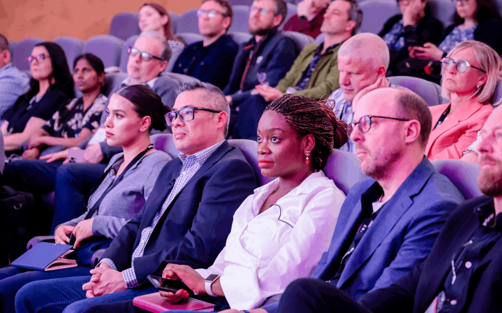 The photo is of a close-up on audience of attendees at the RNIB showcase event. The people pictured are sitting in cinema seats to watch Nyla's Journey short film.