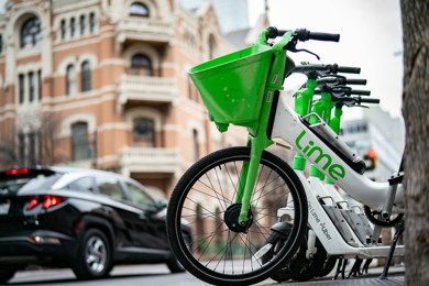 Image of a lined up Lime bikes on the street in a city.