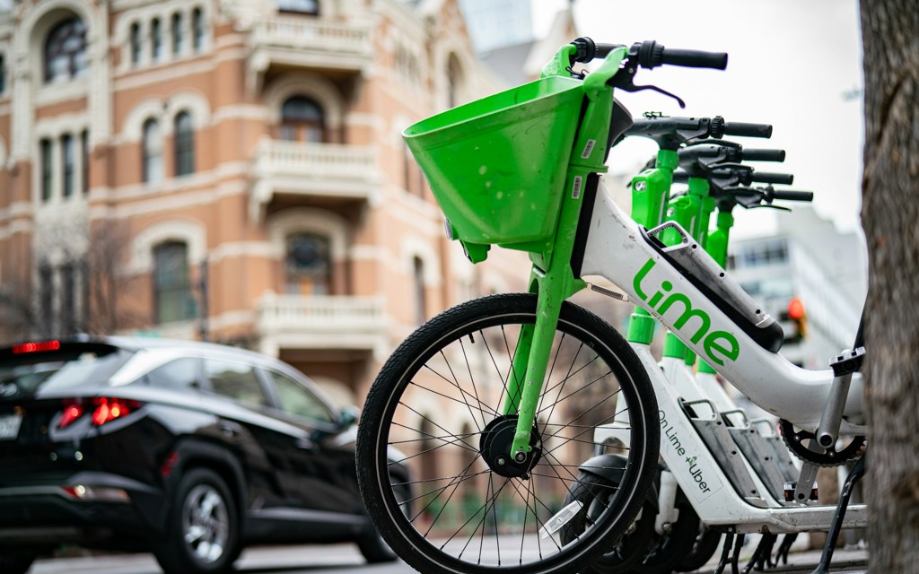 Image of a lined up Lime bikes on the street in a city.