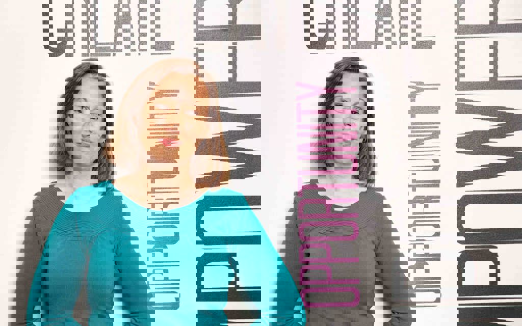 Lisa is standing smiling with her arms behind her back.