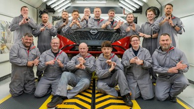 Nissan Sunderland Plant bumper paint team using British Sign Language gestures around a red car bumper.